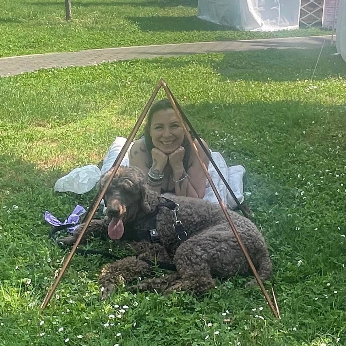 Sabrina con il suo cane a pelo scuro e riccio in giardino, sotto una tenda triangolare